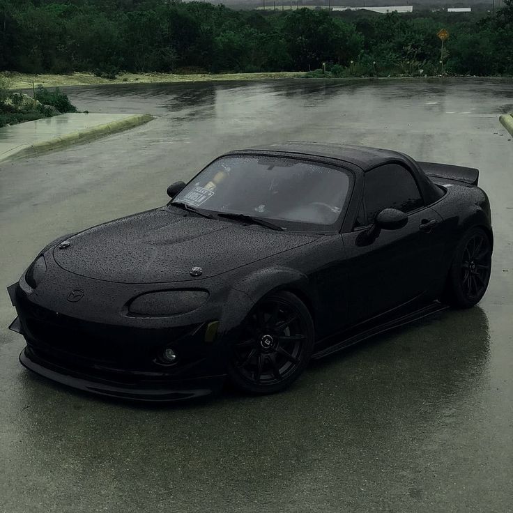 a black sports car is parked in the rain