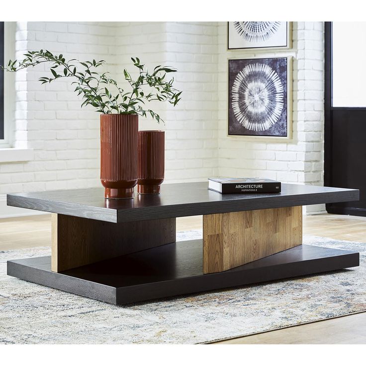 a coffee table with two vases on it and a rug in front of it