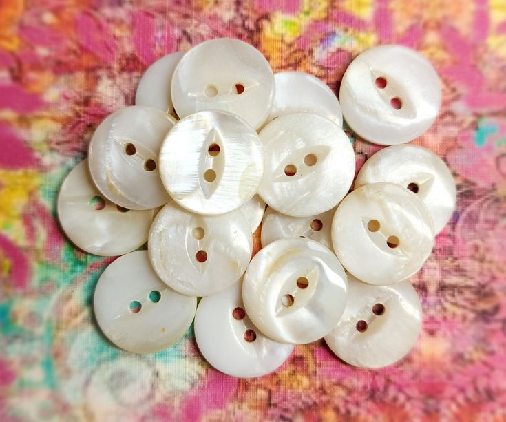 a pile of white buttons sitting on top of a pink and yellow table cloth with flowers