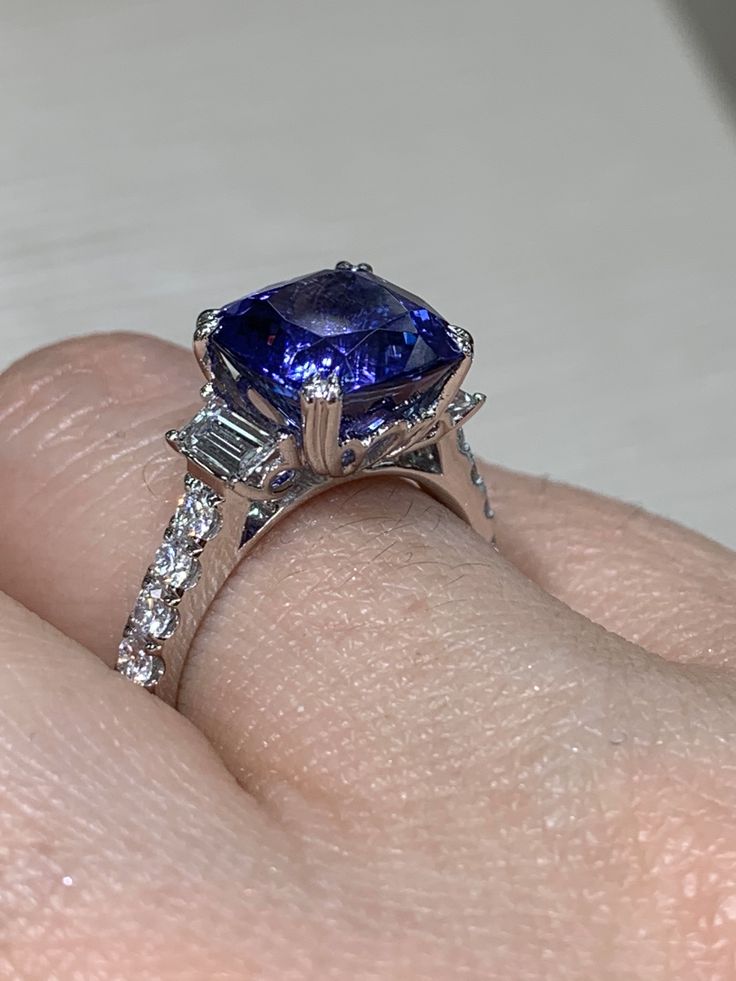 This exquisite Tanzanite & Baguette Diamond Ring features a stunning center stone, two shimmering baguette side diamonds - evoking a sense of timeless elegance and sophistication. An effortless beauty, the ring's immaculate craftsmanship is a testament of its timeless craft and luxurious heritage. Metal: 18K White GoldDiamond Shape: Baguette-cuts & Round Brilliant-CutsDiamond Weight: 2 Baguette 0.42ct tw & 10 Round Brilliant cuts 0.44ct twGemstone Details: 1 Tanzanite 4.36ct Estimated production Baguette Diamond Ring, Baguette Diamond Rings, Effortless Beauty, Tanzanite Diamond, Baguette Cut, Baguette Diamond, Round Brilliant Cut, Round Brilliant, Timeless Elegance