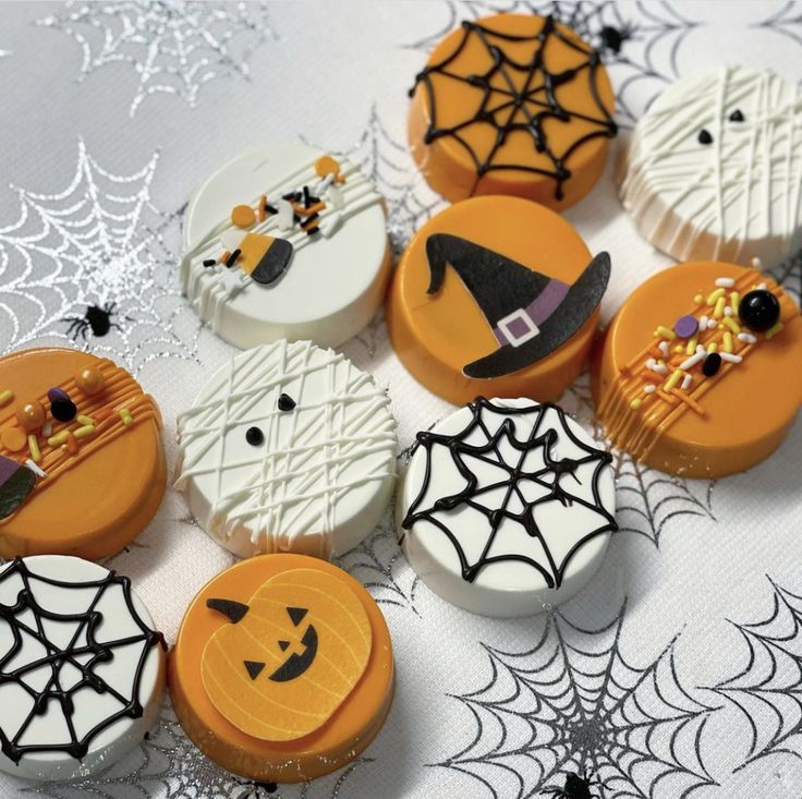 some decorated cookies are on a table with spider webs and pumpkins in the background