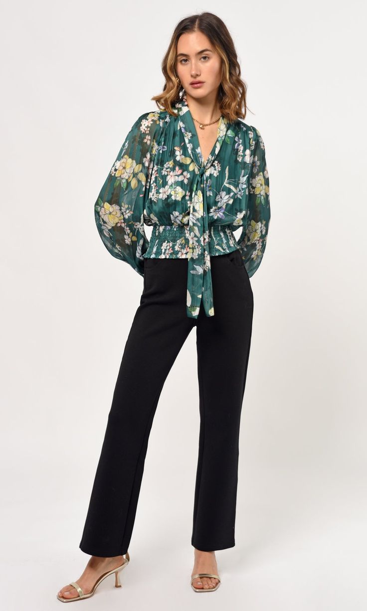 The Estelle neck tie blouse features a high neck collar that can be tied in any form or even left alone for that open tie look. The puff sleeves, floral fabric, and smocked waist add a touch of elegance to this style. Blouse Floral Tie front Puff sleeve Long sleeve Smocked waist Self: 100% Polyester Lining: 92% Polyester, 8% Spandex Length: 21" Chest: 19 1/2" Hand wash in cold water. Lay flat to dry. Low iron. Style #: G239T6868 Elegant Green Floral Print Blouse, Chic Long Sleeve Smocked Top With Floral Print, Elegant Green Top With Gathered Sleeves, Chic Green Top With Gathered Sleeves, Green Long Sleeve Smocked Top, Chic Green Tops With Gathered Sleeves, Green Long Sleeve Smocked Top With Smocked Cuffs, Green Smocked Top With Smocked Cuffs For Fall, Chic Smocked Top For Work