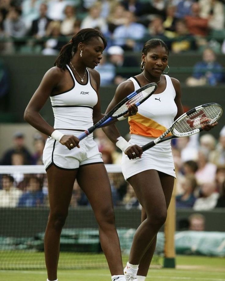 two female tennis players are standing on the court