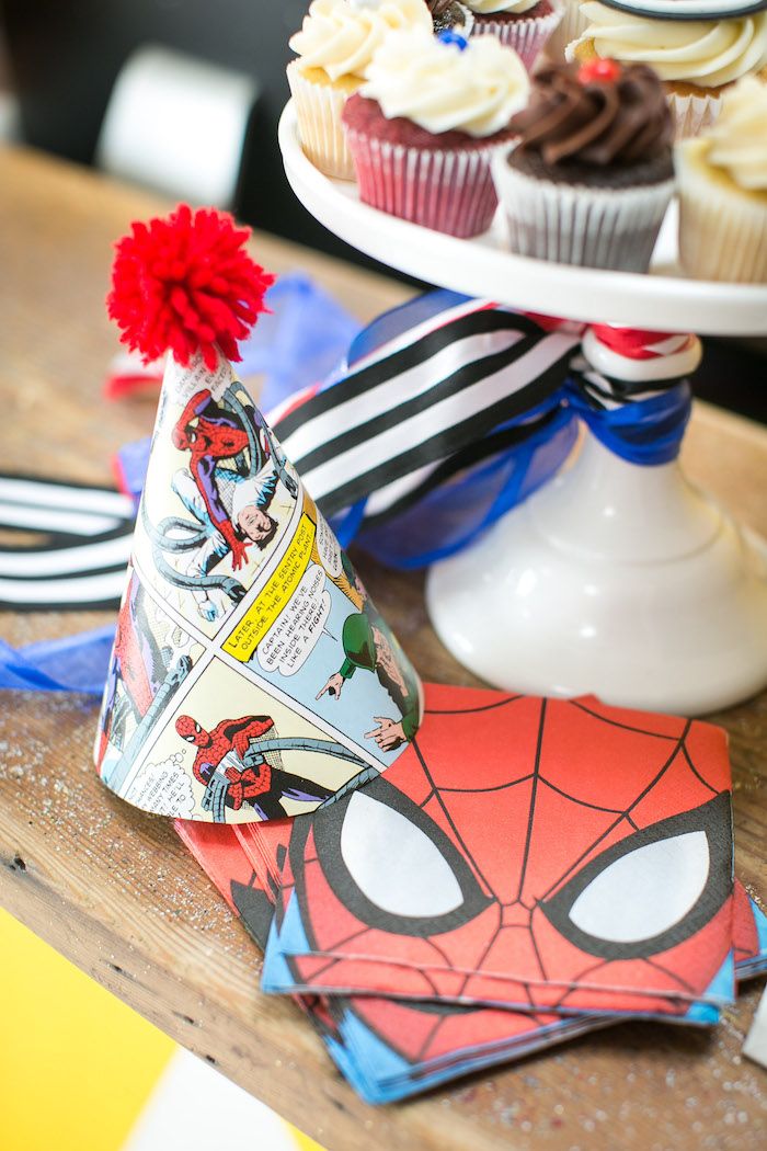 cupcakes and spiderman napkins on a wooden table with other items in the background