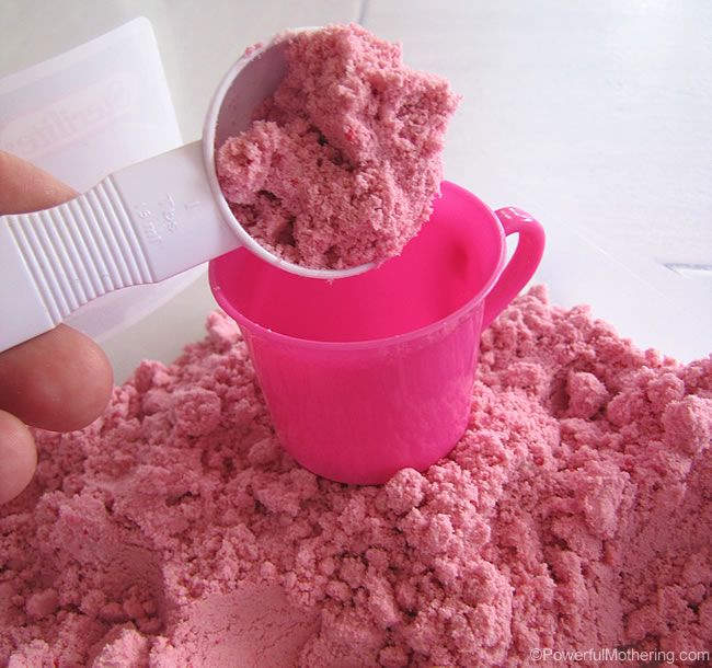 a person is scooping pink colored powder into a bowl