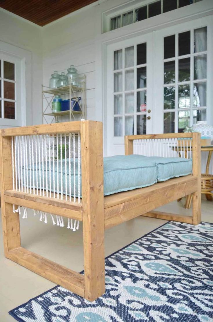 a wooden day bed sitting on top of a blue rug in front of a white house