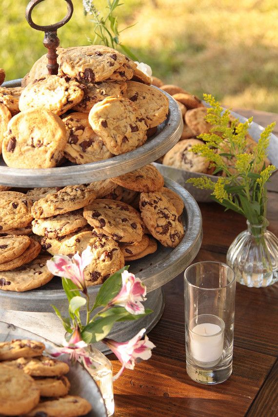 three tiered trays filled with cookies and flowers on top of a wooden table