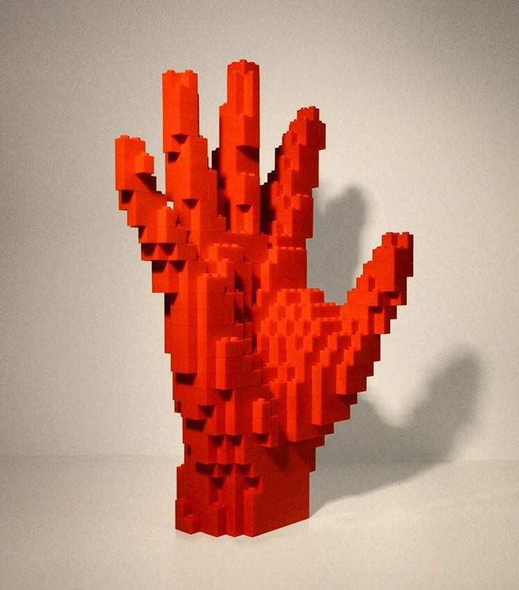 an orange hand made out of legos on a white surface with no one in it