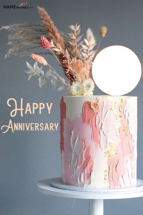 a pink and white cake with flowers on top that says happy anniversary written in gold lettering