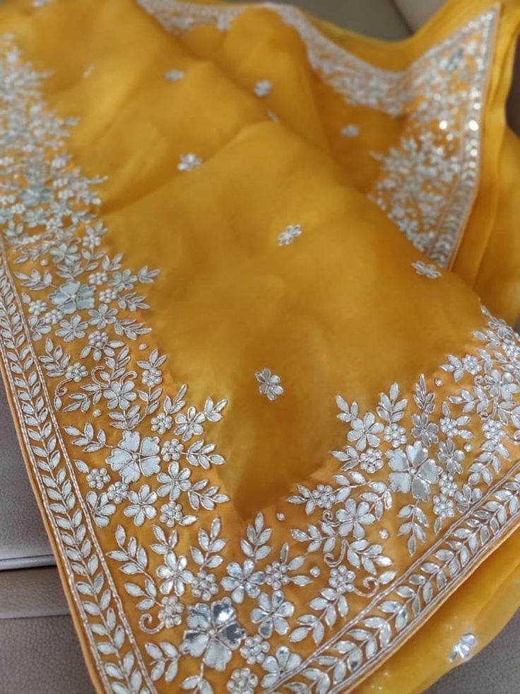 Update! - Zynah covered by LBB - https://lbb.in/bangalore/zynah-designs-handloom-sarees/ This is a precious organza saree in charming yellow color with gotapatti, zardosi, pearl work, and cutwork embroidery, especially for Organza Lovers. The saree features a beautiful floral butis in gotapatti zardosi embroidery work all over the saree. The border is decorated with florals and leaves in gotapatti, zardosi embroidery, adorned with cut-work, and is highlighted with embroidery and pearl work. Colo Traditional Silk Sharara With Dori Work, Traditional Tissue Silk Sharara With Cutdana, Traditional Semi-stitched Blouse Piece With Gota Work, Embroidered Tissue Silk Fabric With Gota Work, Wedding Saree With Gota Work For Transitional Season, Traditional Yellow Saree With Gota Work, Gota Work Embroidered Fabric For Designer Wear, Embroidered Fabric With Gota Work For Designer Wear, Silk Traditional Wear With Handwork