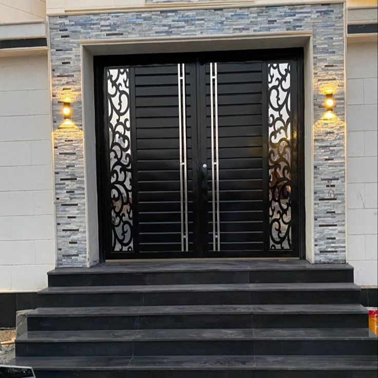 the front entrance to a house with two black doors and steps leading up to it