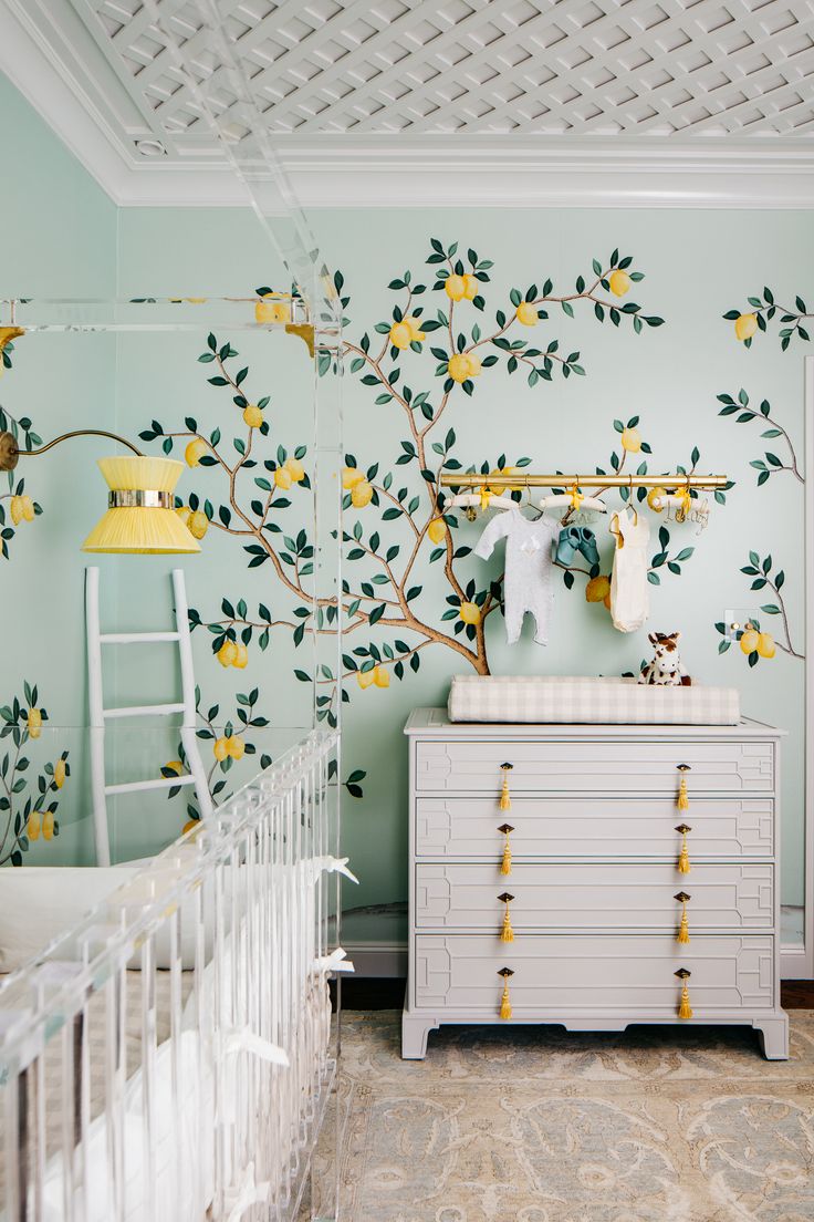 a baby's room decorated with yellow and green flowers on the wall, white crib in foreground