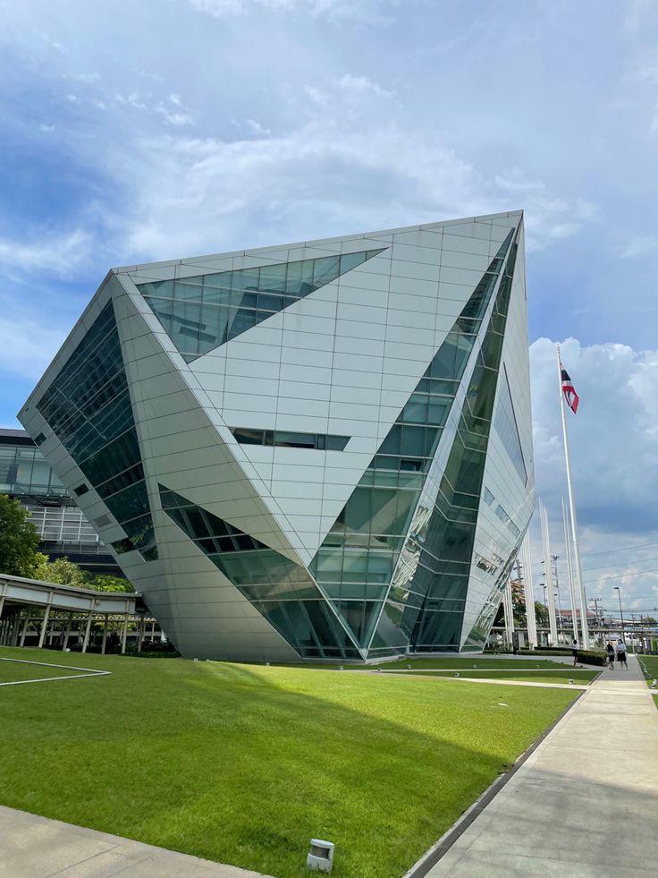 a large building that is next to a grassy field with flags on it's sides