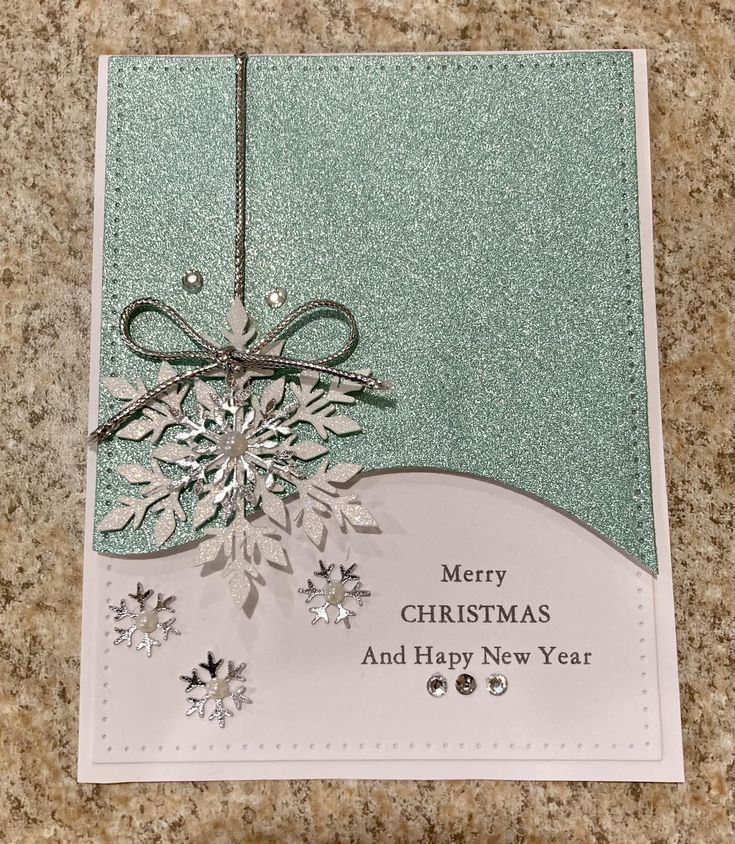 a merry christmas card with snowflakes on it and a bow hanging from the front