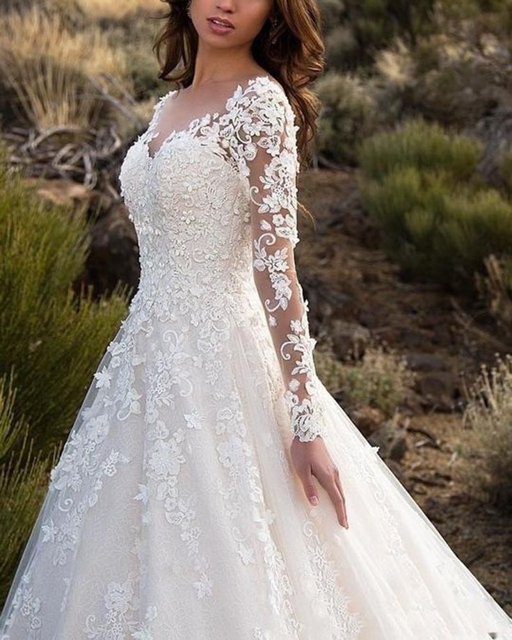 a woman wearing a wedding dress with long sleeves and lace detailing on the bouncy