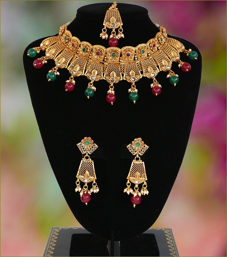 "This Gorgeous dream necklace set with an intricate design in 22KT gold plating. This high quality choker necklace deco intermittently studded around with ruby and emerald round synthetic stones and complete with pair of matching earrings and tikka. 1 x Necklace approx. 5 inches Collar-Wide . Back adjustable rope is attached. 1 x Pair of Earrings 2.75\" Length from top to bottom. *Adjustable & Appropriate for All Neck Sizes. Perfect for a bride in wedding or party wear jewelry set." Ornate Hand Set Gold Plated Jewelry, Ornate Hand-set Gold-plated Jewelry, Festive Filigree Metal Jewelry, Festive Metal Filigree Jewelry, Ornate Meenakari Gold Plated Jewelry, Ornate Gold Plated Meenakari Jewelry, Ornate Meenakari Gold-plated Jewelry, Formal Kundan Choker With Intricate Design, Ceremonial Kundan Jewelry With Elegant Design