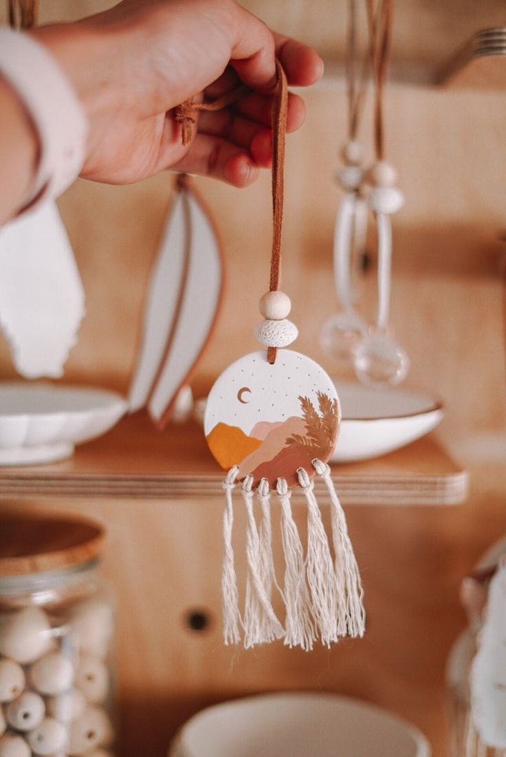 a hand holding a wooden decoration on top of a shelf next to plates and bowls