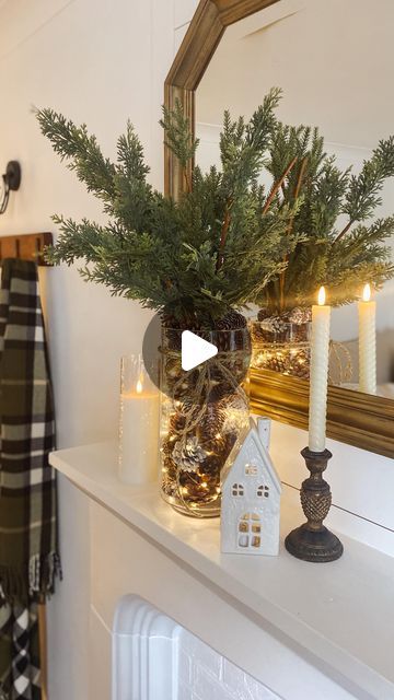 a mantel decorated with candles and greenery in front of a mirror on top of a mantle