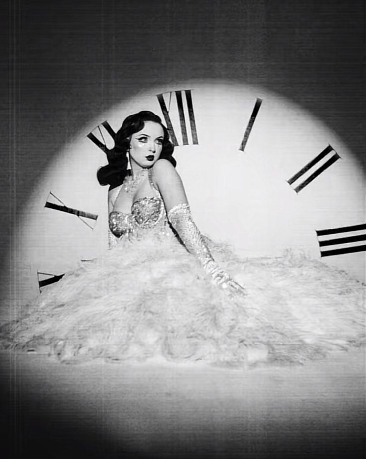 a woman sitting in front of a large clock