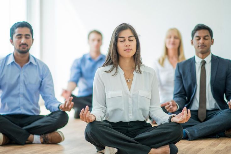 a group of people sitting on the floor in yoga poses, with one woman meditating