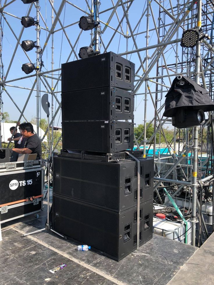 several speakers are stacked on top of each other in front of a building with scaffolding