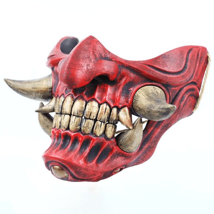 a red mask with horns and fangs on it's face is seen against a white background