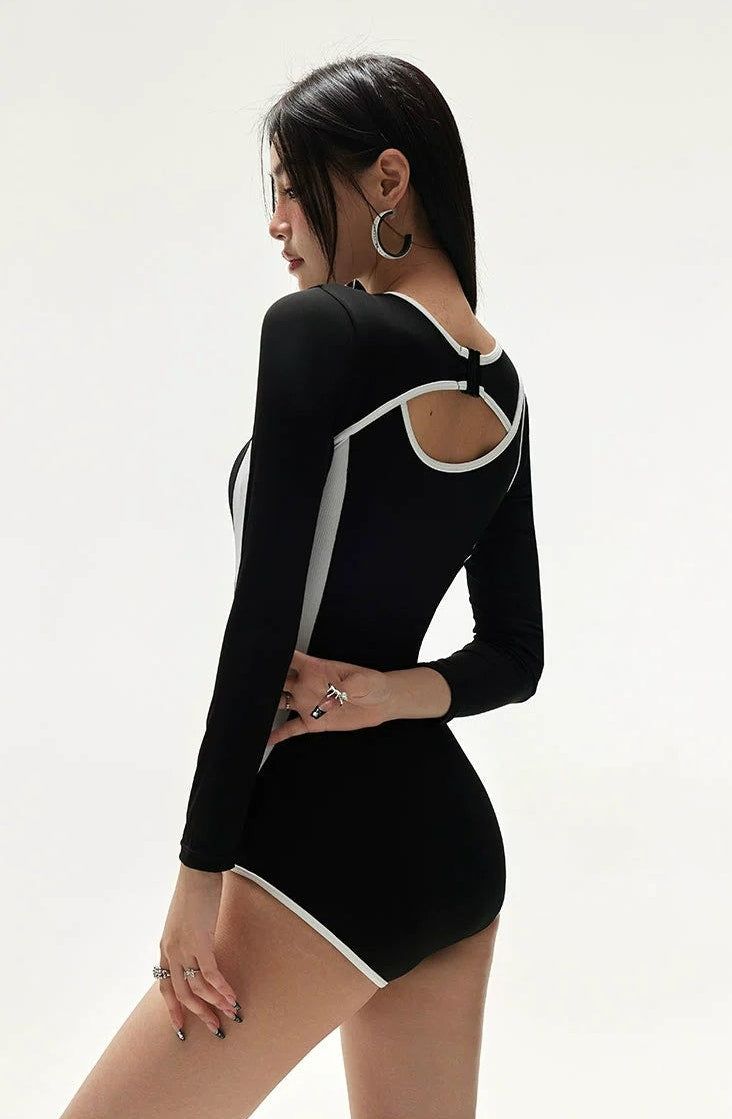 Make a statement by the poolside with this daring Cutout Two-Tone Contrast Hem Long Sleeve Swimsuit. Crafted for those who appreciate a touch of drama, this unique swimsuit features long sleeves, a sophisticated cutout design, and a striking contrast hem. Constructed from premium fabric that shapes comfortably to your body, it's not only quick-drying and durable but also provides excellent elasticity and breathability for all-day wear. Ideal for leisure swimming or a bold fashion statement at be Summer Long Sleeve High Stretch Bodysuit, Chic Spring Swimming Bodysuit, Stretch Long Sleeve Bodysuit For Summer, Chic Bodysuit For Swimming In Spring, Summer Long Sleeve Stretch Bodysuit, Chic Spring Bodysuit For Swimming, Trendy Fitted Bodysuit For Poolside, Long Sleeve Bodysuit With Thumbholes For Summer, Chic High Stretch Swimming Bodysuit