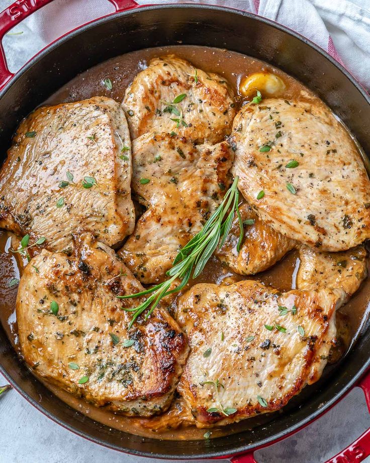 pork chops and gravy in a skillet on a red and white cloth