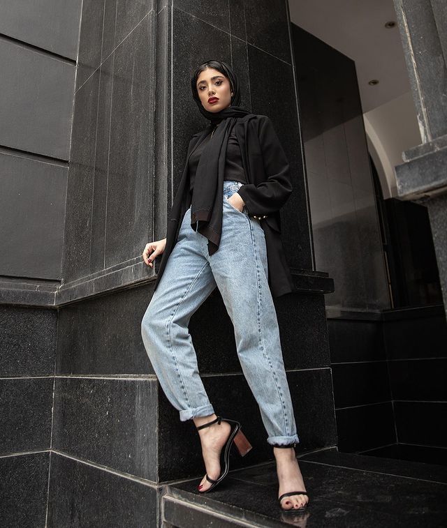 a woman standing on the steps in front of a building wearing high heels and a black jacket