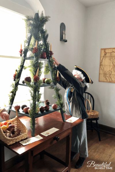 an old man is decorating a christmas tree with pine cones and other holiday decorations