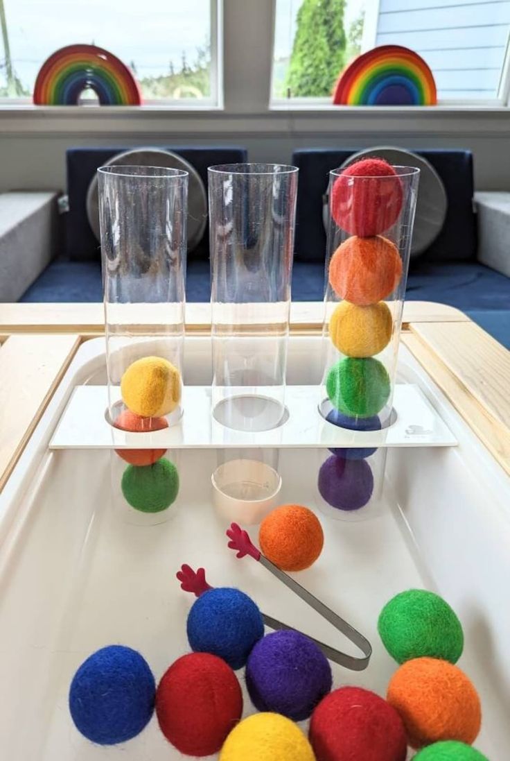 colorful balls and cups on a tray in front of windows