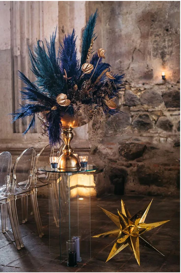 a glass table topped with a vase filled with blue and gold flowers next to a star