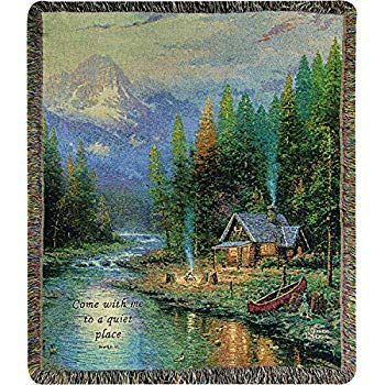 a tapestry depicting a cabin on the river with mountains in the background and trees around it