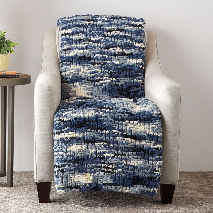 a chair with a blue and white blanket on it next to a small potted plant