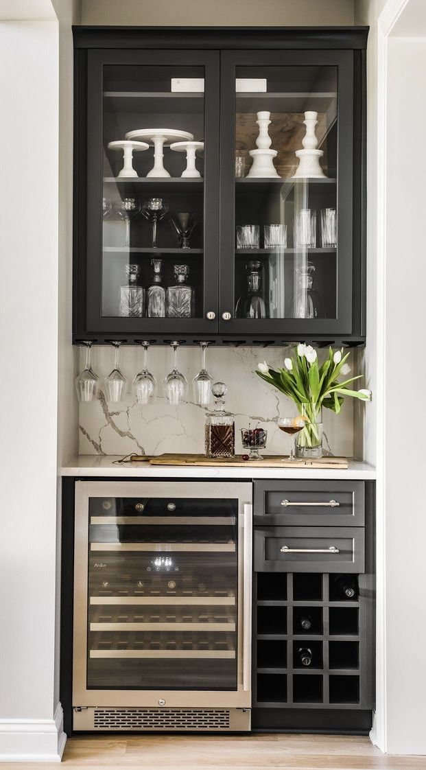 a kitchen with black cabinets and glass doors on the front, white walls and wood floors