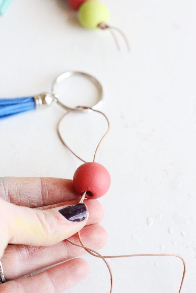 a person holding a string with beads attached to it on a white table next to other items