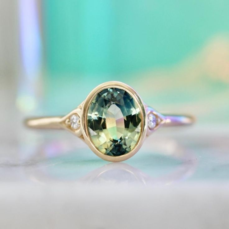 Why I Love It: This divine morsel features an ethereal 1.43 carat oval cut parti sapphire center with stunning hues of green, blue, and yellow. A perfectly matched pair of white round brilliant cut diamonds in the shoulders and delicious 14k Yellow Gold finish off this stunning engagement ring. Sits low and flush to the finger. The Details: 14k Yellow Gold 1.43 Carat Green Oval Cut Parti Sapphire Madagascar Origin .04 Carats Total of White Round Brilliant Cut Canadian Diamonds Current Ring Size Parti Sapphire, Green Oval, Stunning Engagement Ring, Round Brilliant Cut Diamond, Madagascar, Rose Cut, Oval Cut, Round Brilliant, Gold Finish