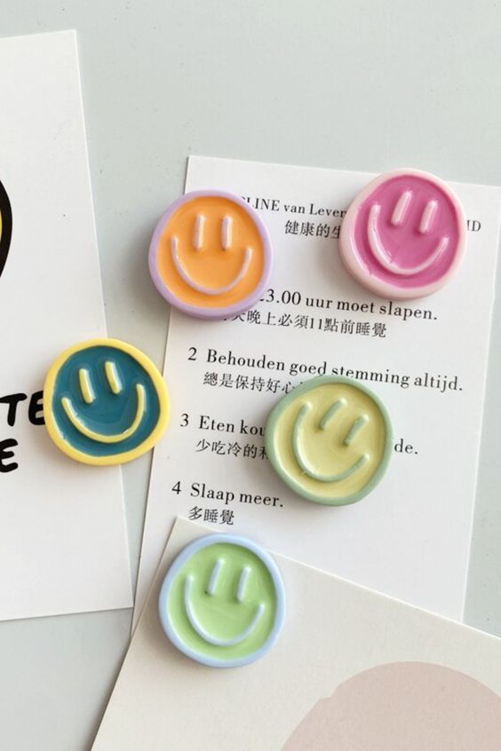 three different colored smiley face buttons sitting on top of a piece of paper next to each other