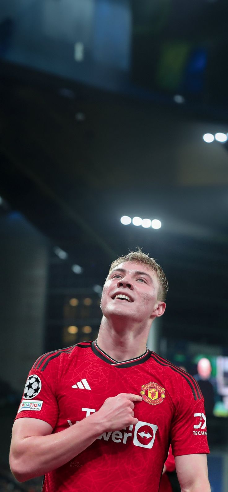 a man standing in front of a crowd wearing a red shirt and holding a soccer ball