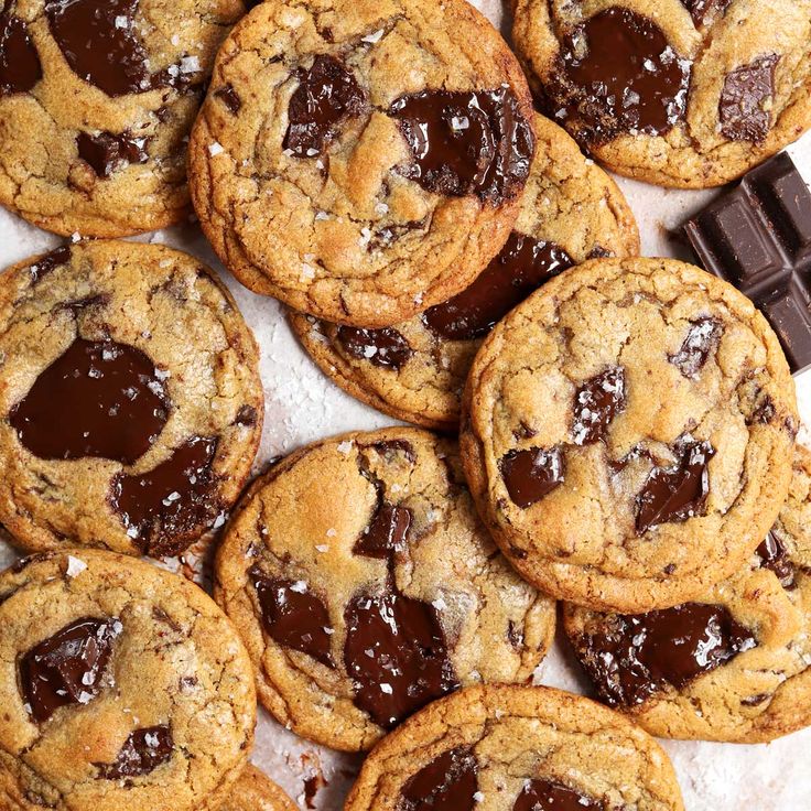 chocolate chip cookies are piled on top of each other next to a bar of chocolate