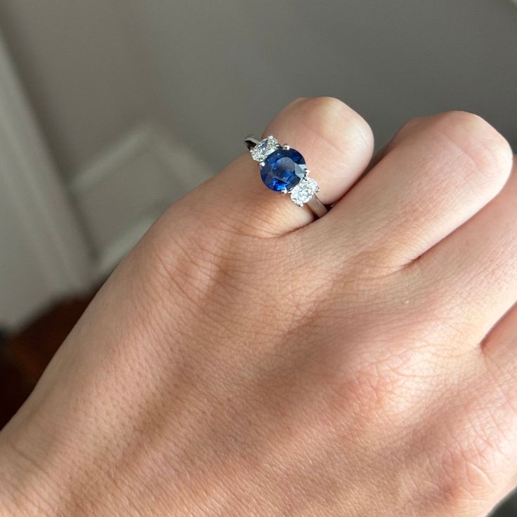 a woman's hand with a blue and white diamond ring on her left hand