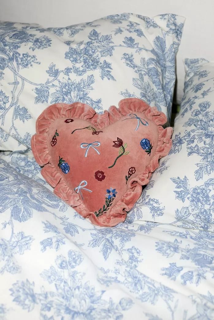 a heart shaped pillow sitting on top of a bed covered in blue and white sheets