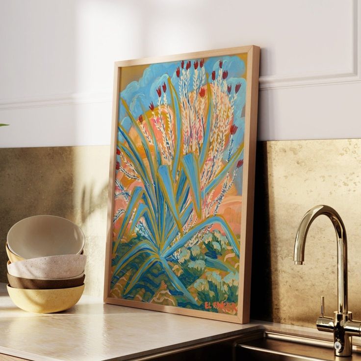 a painting sitting on top of a kitchen counter next to a sink and faucet