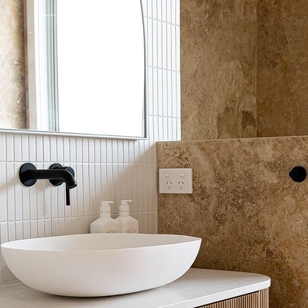 a bathroom sink sitting under a mirror next to a counter top with a soap dispenser