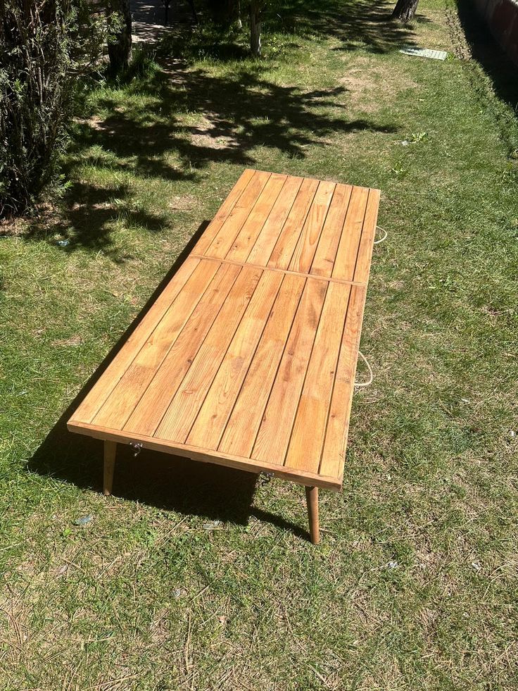 a wooden table sitting on top of a lush green field