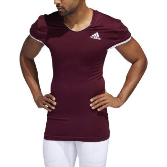 a man standing with his hands on his hips wearing a maroon shirt and white pants