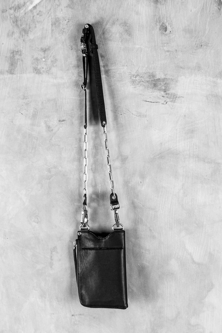 a black and white photo of a handbag hanging on a wall with a chain attached to it