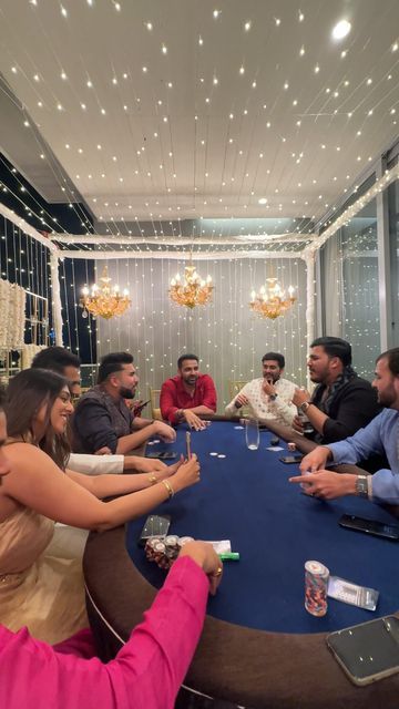 a group of people sitting around a table with cards in front of them and lights on the wall behind them