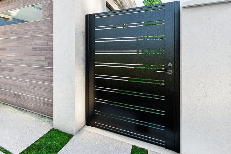 a modern gate is shown in front of a house with grass and bushes on the side