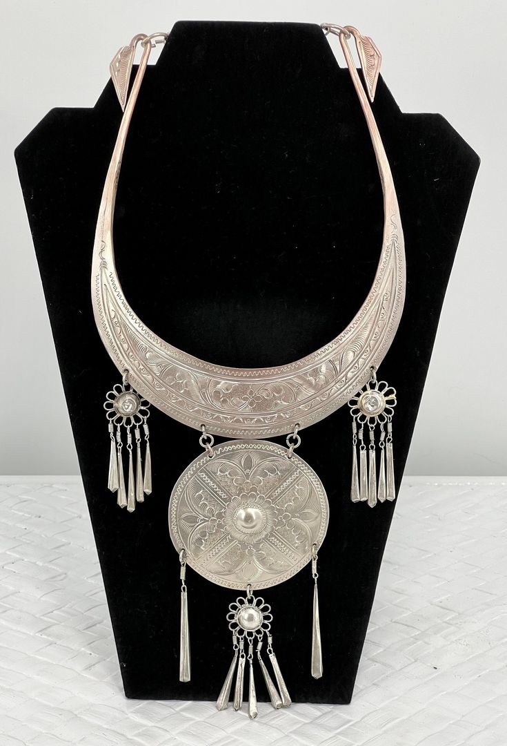 "Vintage Thailand Collar Necklace/Etched Floral/Silver Platted/12\" L x 5 1/2\". Stunning Vintage Hmong Miao Torque silver necklace . Silver plate brass ceremonial Torque Necklace with fringe & bells. Hand engraved with botanical scroll motif & elongated links. Hangs and moves beautifully, the bib fits with hook closure. Good vintage condition, the few areas that are showing age are some of the silver around the neck area is faded and the two top dangling flowers are pushed in. Please see pictures for full details. Miao silver is not pure silver, but an alloy of silver, copper and nickel. It's a traditional material for making jewelry by craftsmen of Miao Hmong ethnic tribe. Necklace hangs: 12\" long x 5 1/2\" wide" Ceremonial Silver Medallion Necklace, Silver Medallion Necklace For Ceremonial, Silver Medallion Necklace For Ceremonial Occasions, Ceremonial Silver Etched Necklace, Traditional Silver Etched Necklace, Ceremonial Silver Jewelry With Large Pendant, Ceremonial Etched Silver Necklace, Silver Jewelry With Large Pendant For Ceremonial Occasions, Ceremonial Silver Medallion Jewelry